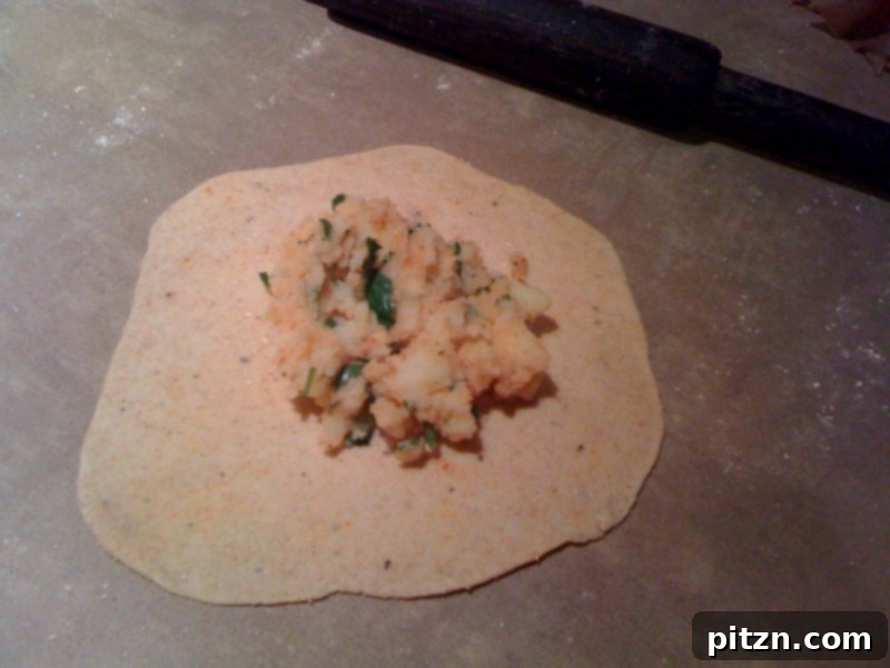 Mom's Aloo Paratha and Sanjeev Kapoor's Baghare Baingan A Flavorful Pairing 4 Step-by-step image showing how to place potato stuffing in the center of a rolled-out dough disc for Aloo Paratha.