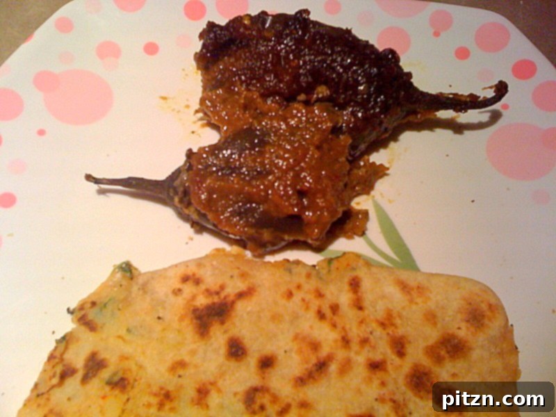Mom's Aloo Paratha and Sanjeev Kapoor's Baghare Baingan A Flavorful Pairing 8 A vibrant plate featuring Baghare Baingan (stuffed eggplant curry) served next to freshly made Aloo Paratha, a perfect Indian meal.