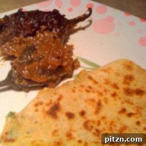 Mom's Aloo Paratha and Sanjeev Kapoor's Baghare Baingan A Flavorful Pairing 3 A beautifully cooked Aloo Paratha, golden brown and puffed, served on a plate ready to be enjoyed.