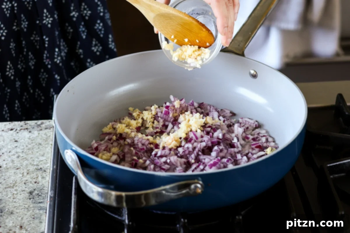 Restaurant-Quality Dal Makhani at Home 9 Chopped onions, garlic, and ginger being added to the skillet to sauté with whole spices.