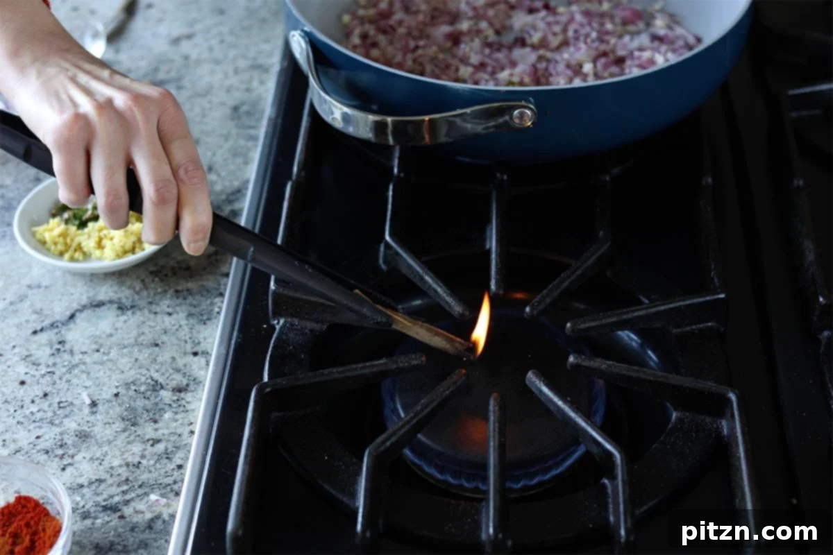 Restaurant-Quality Dal Makhani at Home 10 A small piece of cinnamon stick being lightly charred over a flame to add smoky flavor.