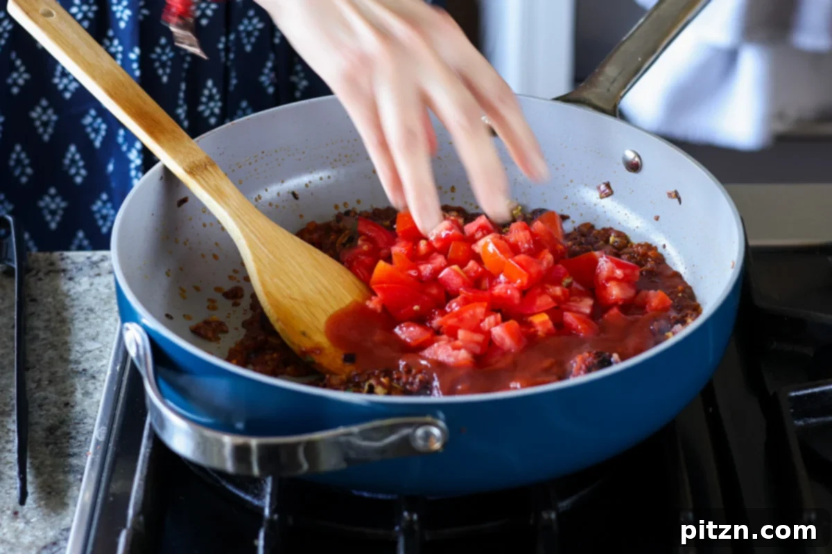 Restaurant-Quality Dal Makhani at Home 12 Tomato puree and chopped tomatoes being added to the spice and onion mixture in the pan.