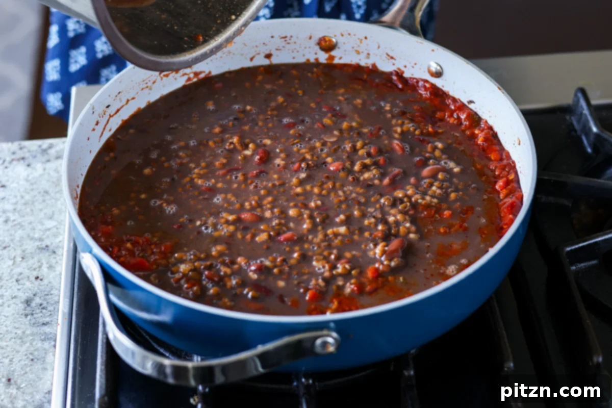 Restaurant-Quality Dal Makhani at Home 14 Cooked black gram and kidney beans being added to the rich tomato and spice base in the pan.