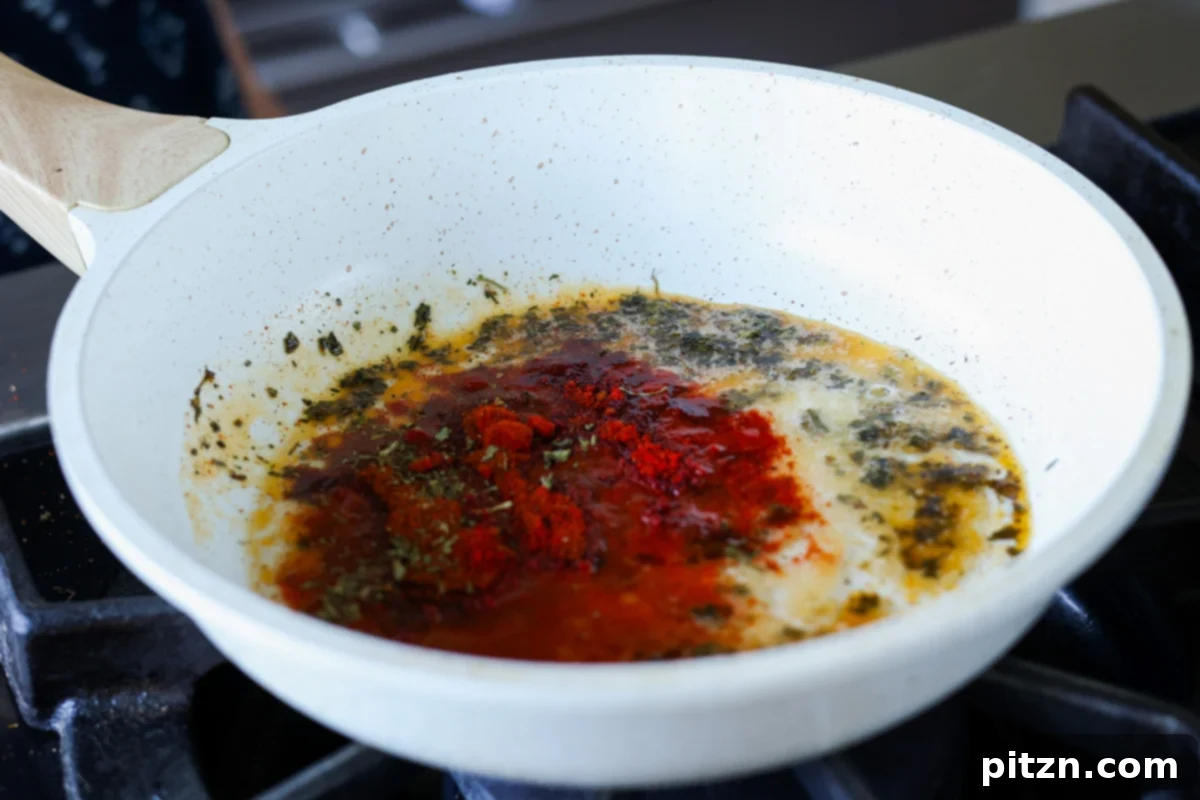 Restaurant-Quality Dal Makhani at Home 17 Kashmiri chili powder being added to melted vegan butter in a small skillet for the spiced oil (tadka).