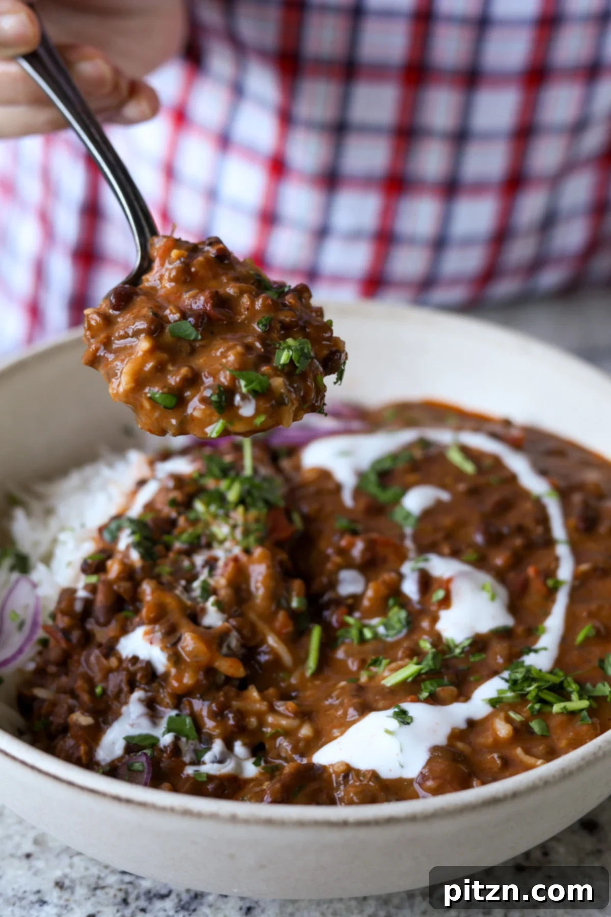 Restaurant-Quality Dal Makhani at Home 4 A spoon scooping up a delicious bite of creamy Dal Makhani, highlighting its rich consistency.