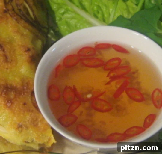 A small bowl filled with homemade Nuoc Cham sauce, garnished with a sliced chili, ready for dipping.