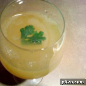 Sweet-Tart Raw Mango Cooler 2 A top down shot of Aam Panna in a glass, garnished with a green herb