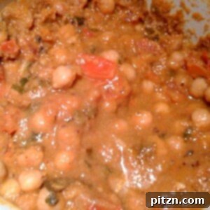 A close up of Kadhai Chole being cooked in a white pan, showcasing its rich texture and spices.