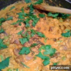 Velvet Mushroom Pea Masala 2 Mushroom Mutter Masala cooking in a pan, being stirred with a wooden spoon, showcasing its rich texture.