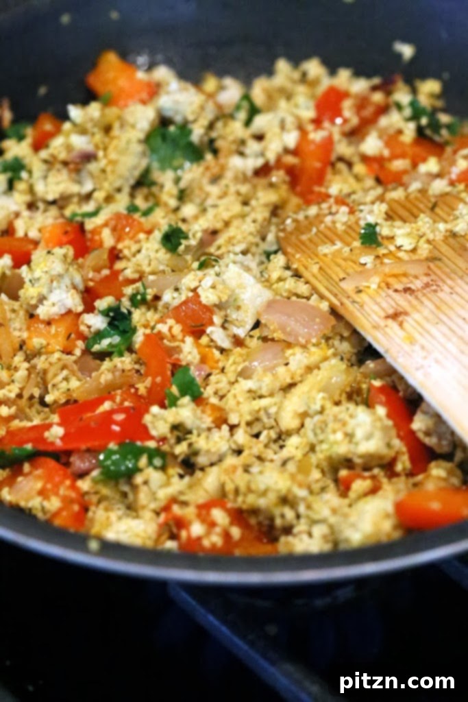 Hemp tofu scramble cooking with spices and greens