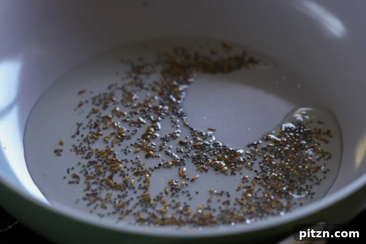 Toasted whole spices (cumin and mustard seeds) sizzling in hot oil