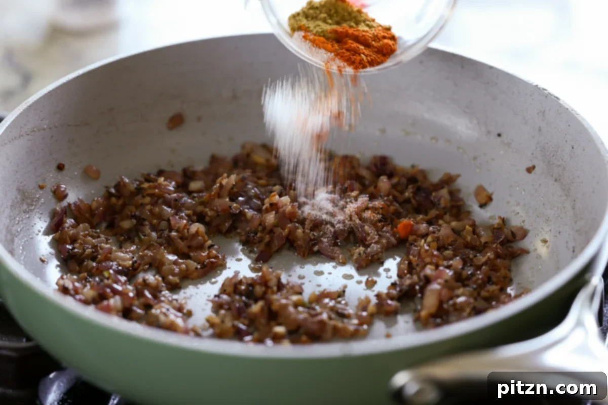 Adding ground spices to the cooked aromatics in the pan