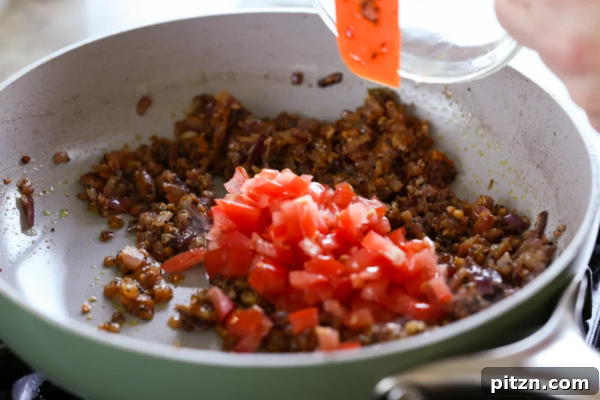 Adding chopped tomato to the pan for the tempering
