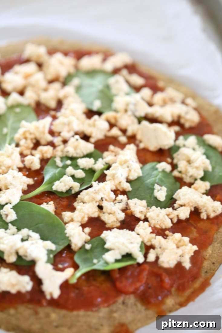 Easy Gluten Free Yeast Free Vegan Pizza Base 8 Topping the par-baked Gluten-free Yeast-free Vegan Pizza Crust with sauce, vegetables, and vegan cheese before the final bake.