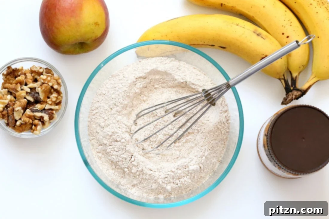 Delicious One-Bowl Vegan Banana Apple Loaf 5 Whisking dry ingredients for One Bowl Vegan Banana Apple Bread. Flour, baking powder, baking soda, spices, and sugar are combined evenly.
