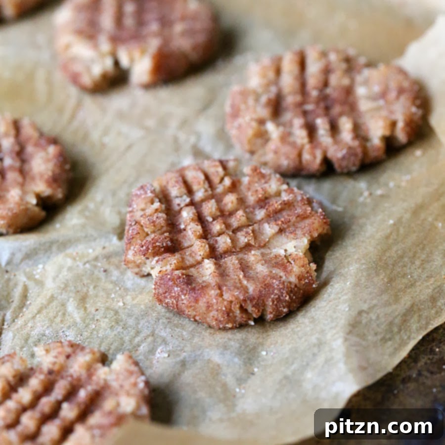 Close-up of baked vegan almond butter snickerdoodles on a parchment-lined baking sheet