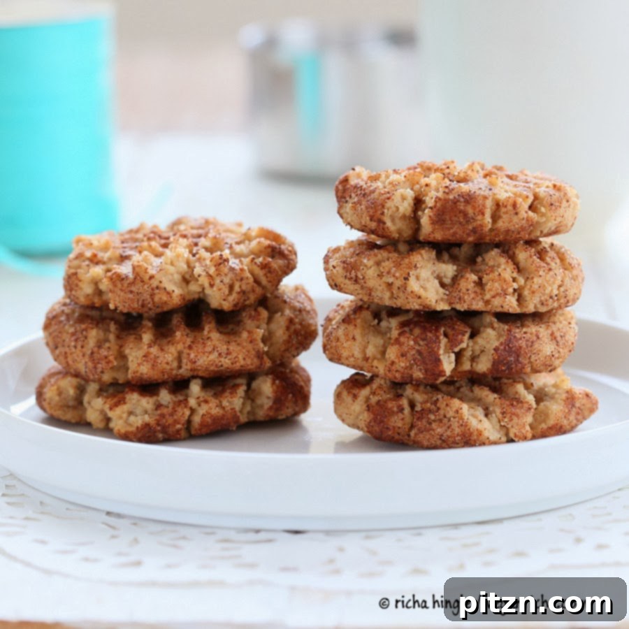 Stacked vegan almond butter snickerdoodles with a bite taken out, showing soft interior