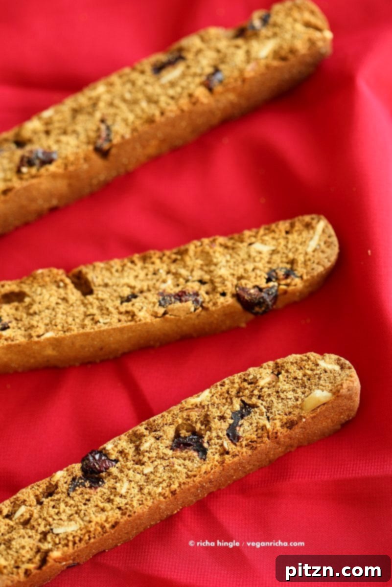 Vegan Gingerbread Biscotti with cranberries, almonds, candied ginger. Easy Crispy Spiced Biscotti Recipe to dunk in a cup of tea. Drizzle with white or dark chocolate. | VeganRicha.com #vegan #gingerbread #biscotti #recipe