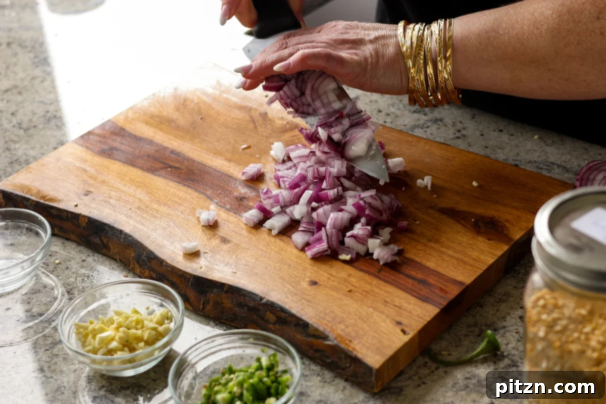 Dal Tadka Lentil Soup Mix in a Jar 13 Chopping a fresh onion into small, even pieces on a cutting board.