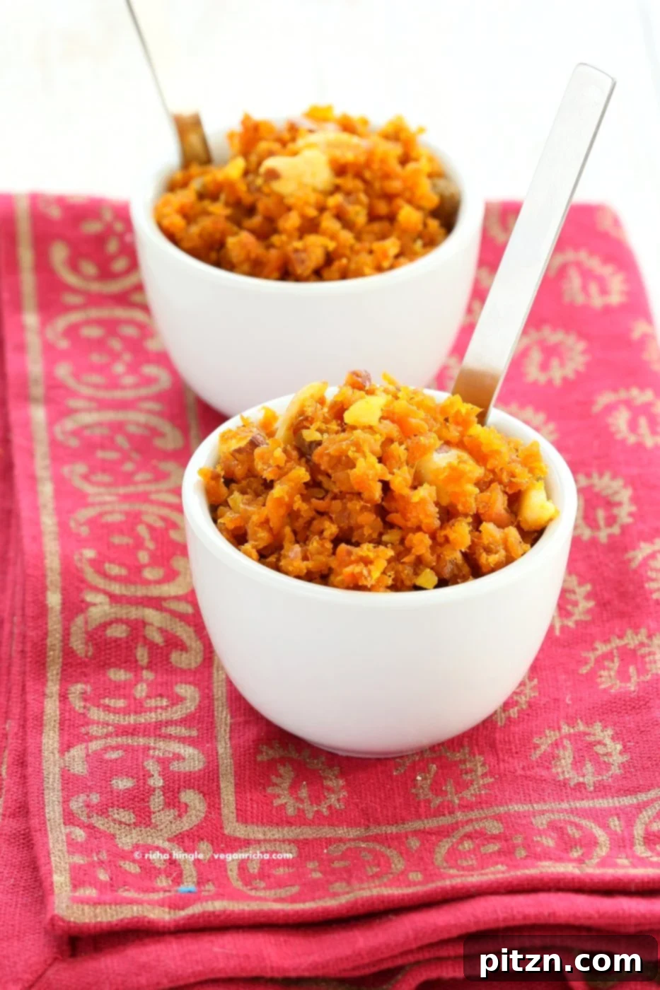 A beautifully presented serving of Vegan Gajar Halwa, garnished with finely chopped pistachios and almonds, highlighting the vibrant orange color and creamy texture. This is a healthy, compassionate, and dairy-free Indian dessert option.