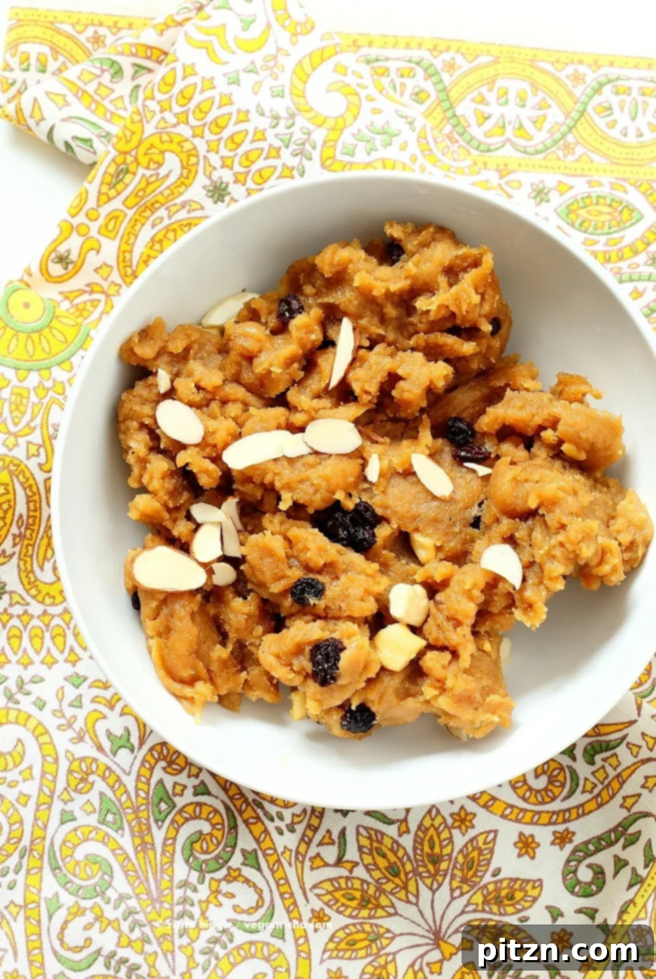 Close-up of a serving of Besan Halwa garnished with nuts, highlighting its inviting texture and golden-brown hue.