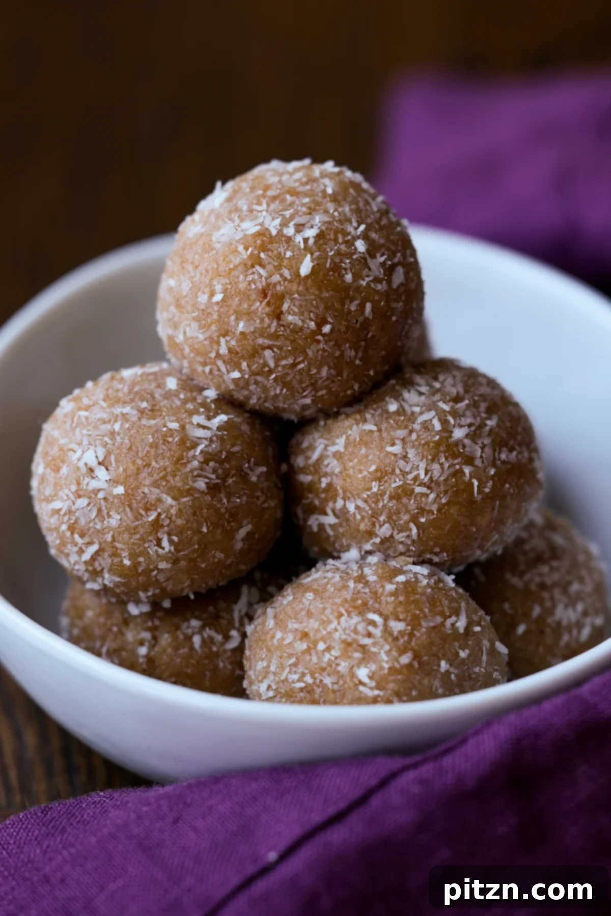 Toasted Cardamom Coconut Ladoo 2 A beautiful pile of golden-brown toasted coconut ladoo arranged elegantly on a white serving plate, ready to be enjoyed.