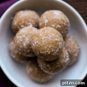 A close-up of beautifully toasted coconut ladoo on a pristine white serving plate.