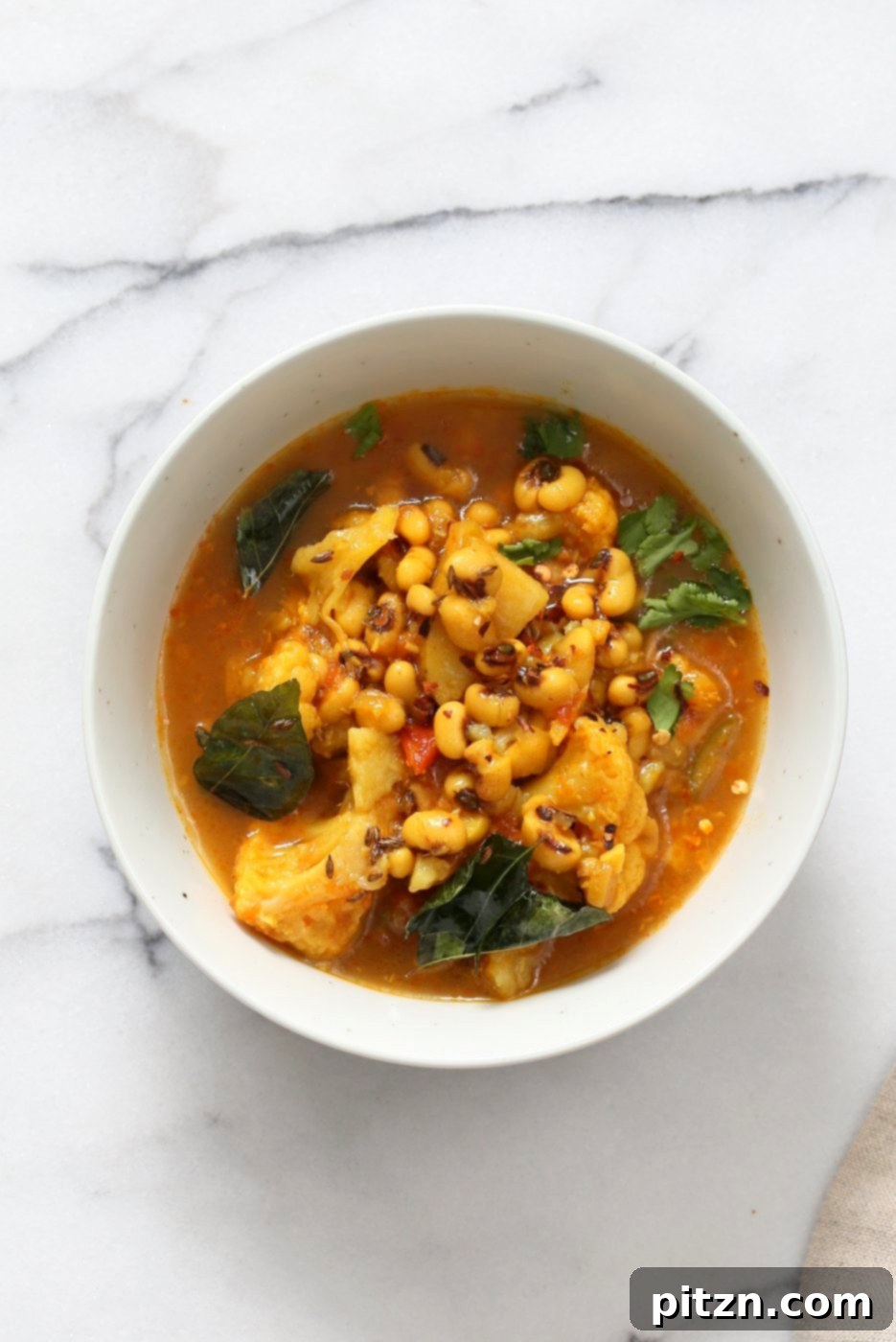 A vibrant bowl of Coconutty Black Eyed Pea Curry with Cauliflower and Potatoes, ready to be served. A delicious and easy Instant Pot Vegetarian Black Eyed Peas Recipe with a saucepan option.