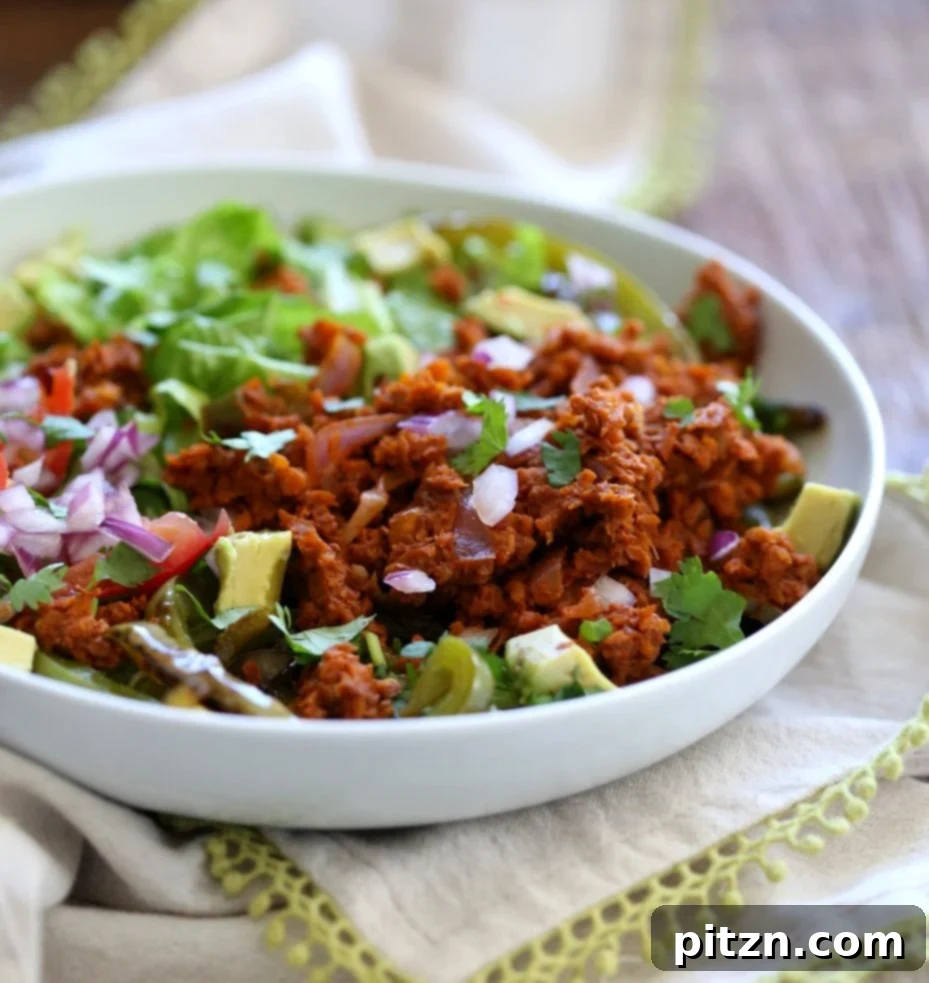 Overhead view of a prepared vegan taco salad bowl, highlighting the carrot walnut "meat", fresh cilantro, and vibrant toppings.