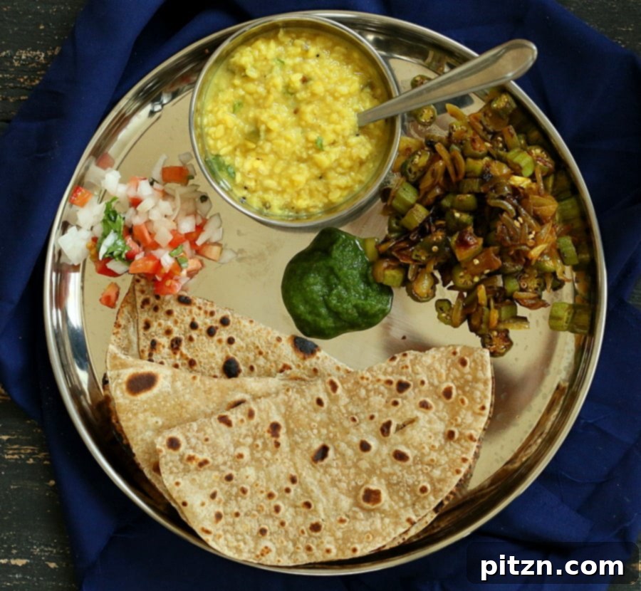 A traditional Indian lunch spread, showcasing Okra and Onion stir fry (Pyaaz Waali Bhindi) as a central dish.