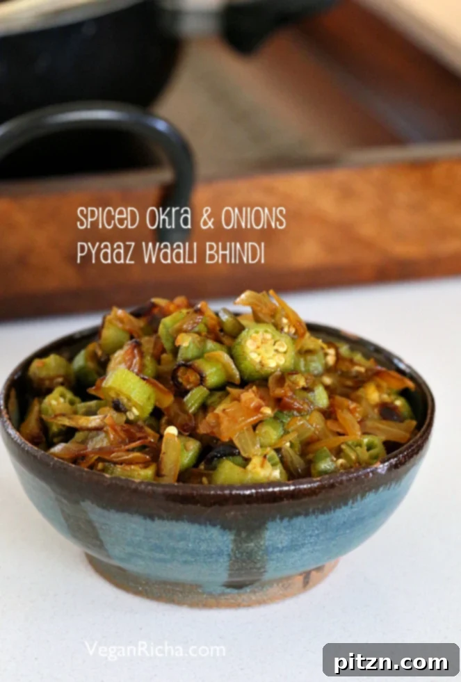 A close-up view of Indian Okra and Onion stir fry (Pyaaz Waali Bhindi Subzi) being cooked in a pan.