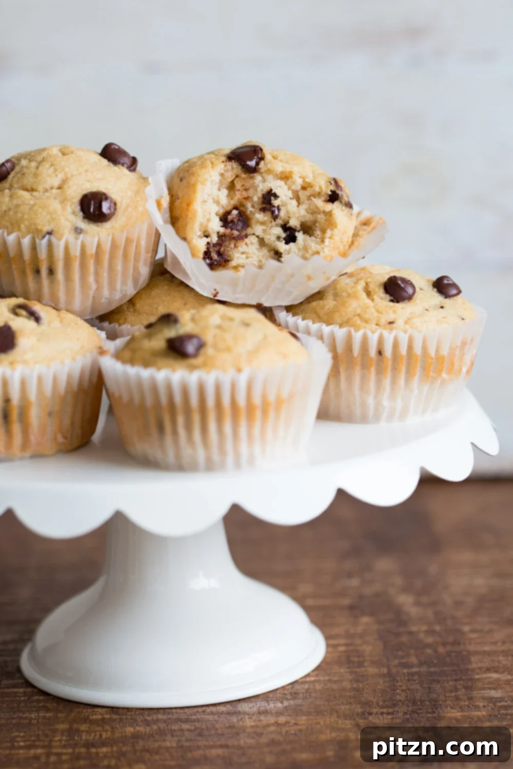 A close-up of fluffy vegan chocolate chip coconut muffins, showcasing their golden-brown tops and rich texture, enticing you to take a bite.