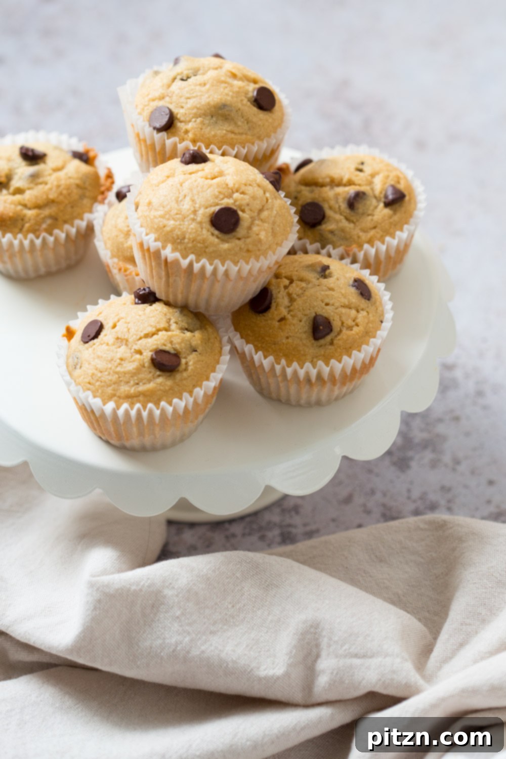 A batch of freshly baked vegan chocolate chip coconut muffins cooling on a wire rack, steam gently rising, ready to be devoured.