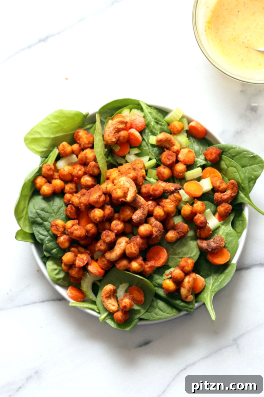Spicy Sriracha Chickpea Cashew Spinach Power Bowl with Golden Curry 6 A vibrant Sriracha Chickpea Spinach Bowl being assembled in a white bowl