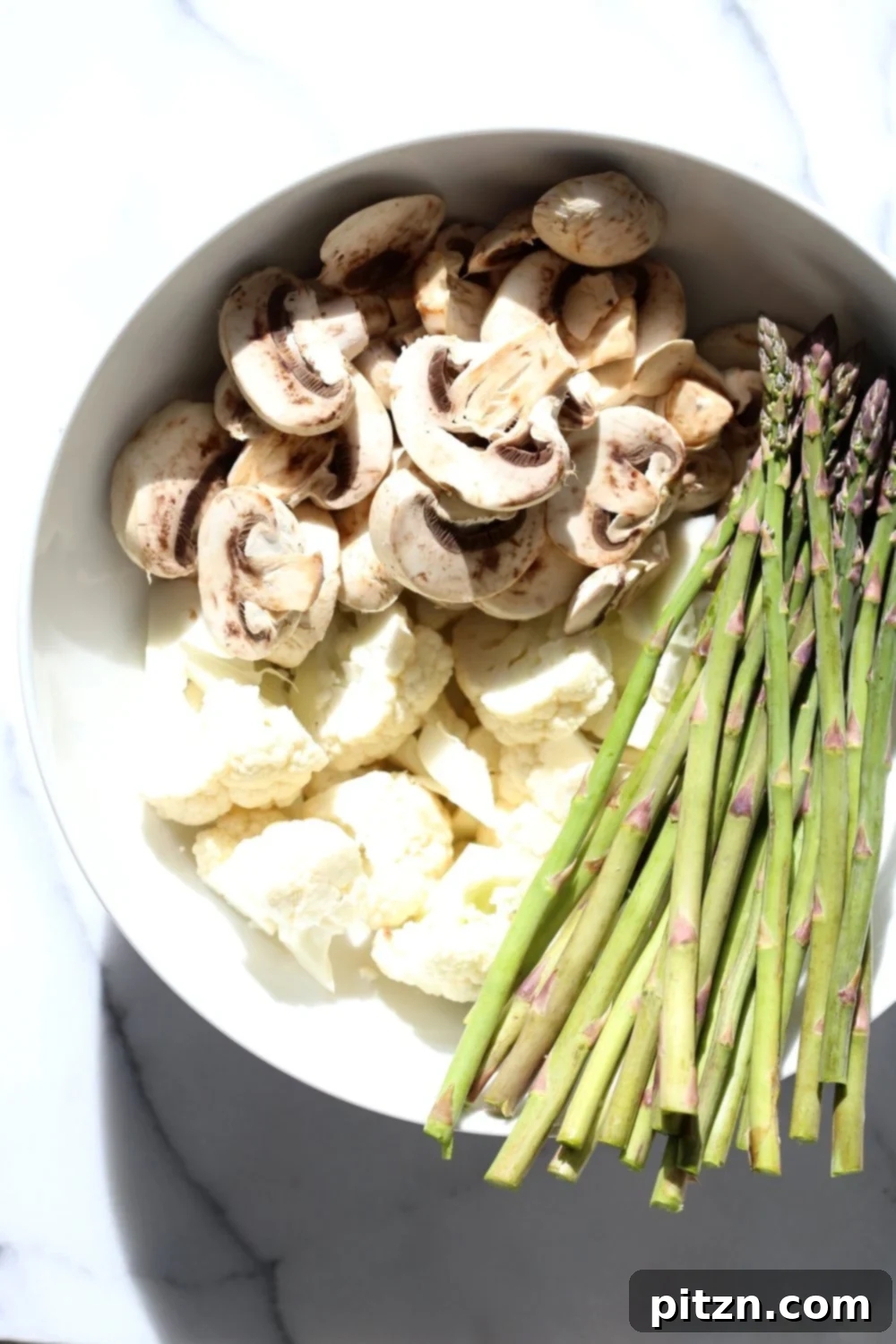 Step-by-step photo: Cauliflower and mushrooms tossed with oil and bulgogi spices on a baking sheet, ready for roasting.