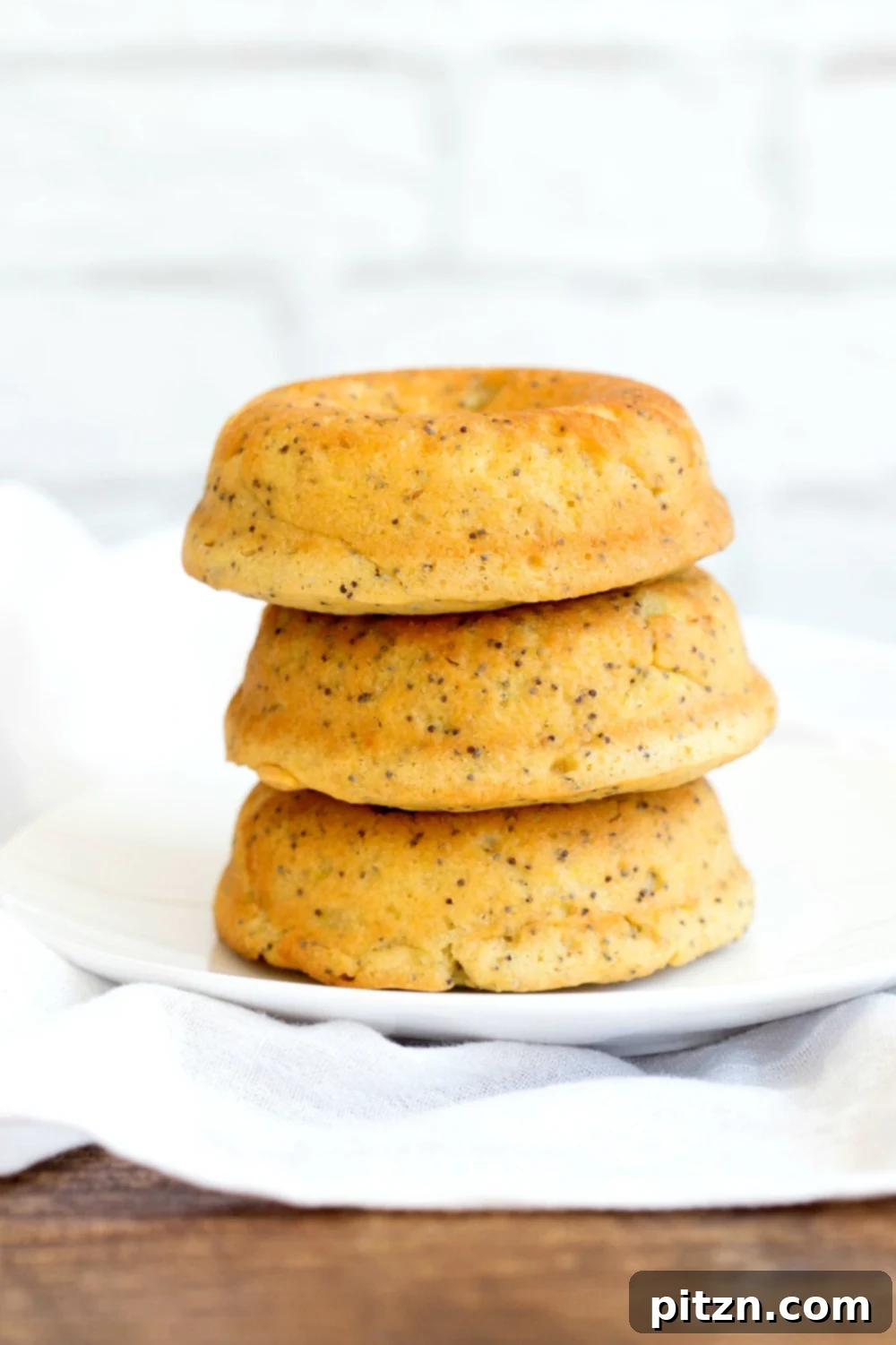 Zesty Vegan Lemon Poppy Seed Delights 4 Close-up of a single Vegan Lemon Poppy Seed Donut, unglazed and showcasing its fluffy crumb and poppy seed specks.
