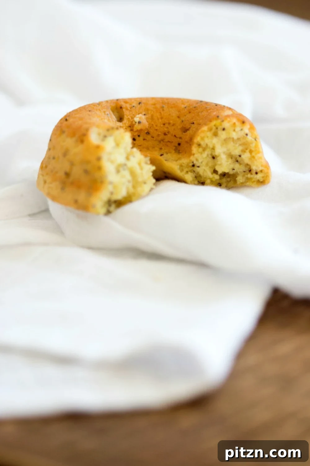 Zesty Vegan Lemon Poppy Seed Delights 6 A close-up of a glazed Vegan Lemon Poppy Seed Donut, showing the delightful texture and poppy seeds embedded in the dough.