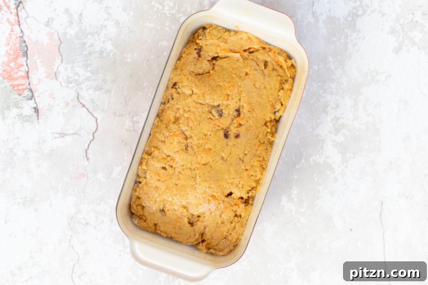 Vegan carrot pumpkin bread unbaked, sitting in a parchment-lined loaf pan before going into the oven.