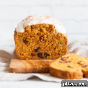 a loaf of vegan pumpkin carrot bread sliced on a chopping board