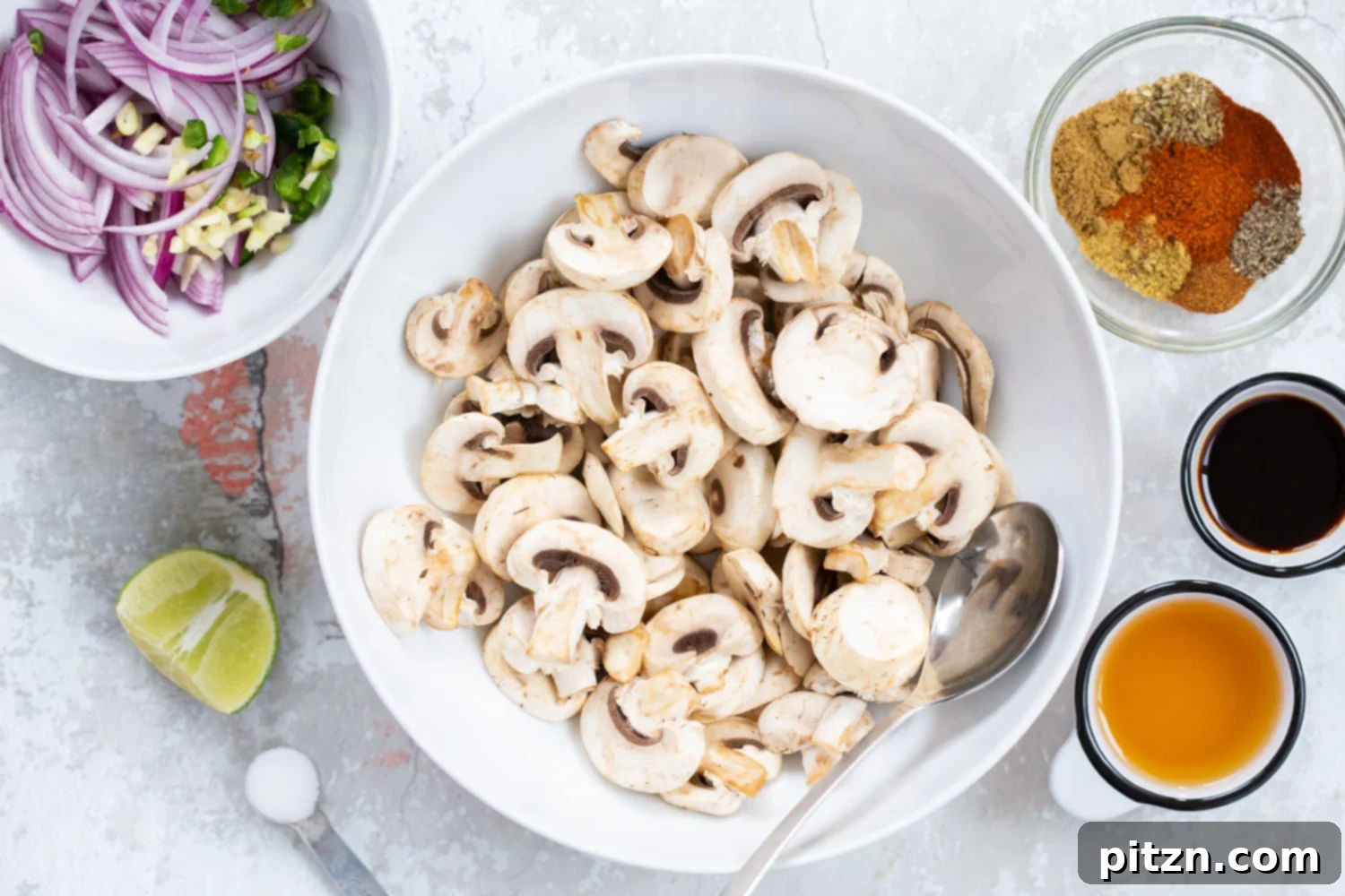 A bowl filled with thinly sliced mushrooms, onions, and various spices, ready to be mixed for Vegan Carnitas, illustrating the initial preparation stage.
