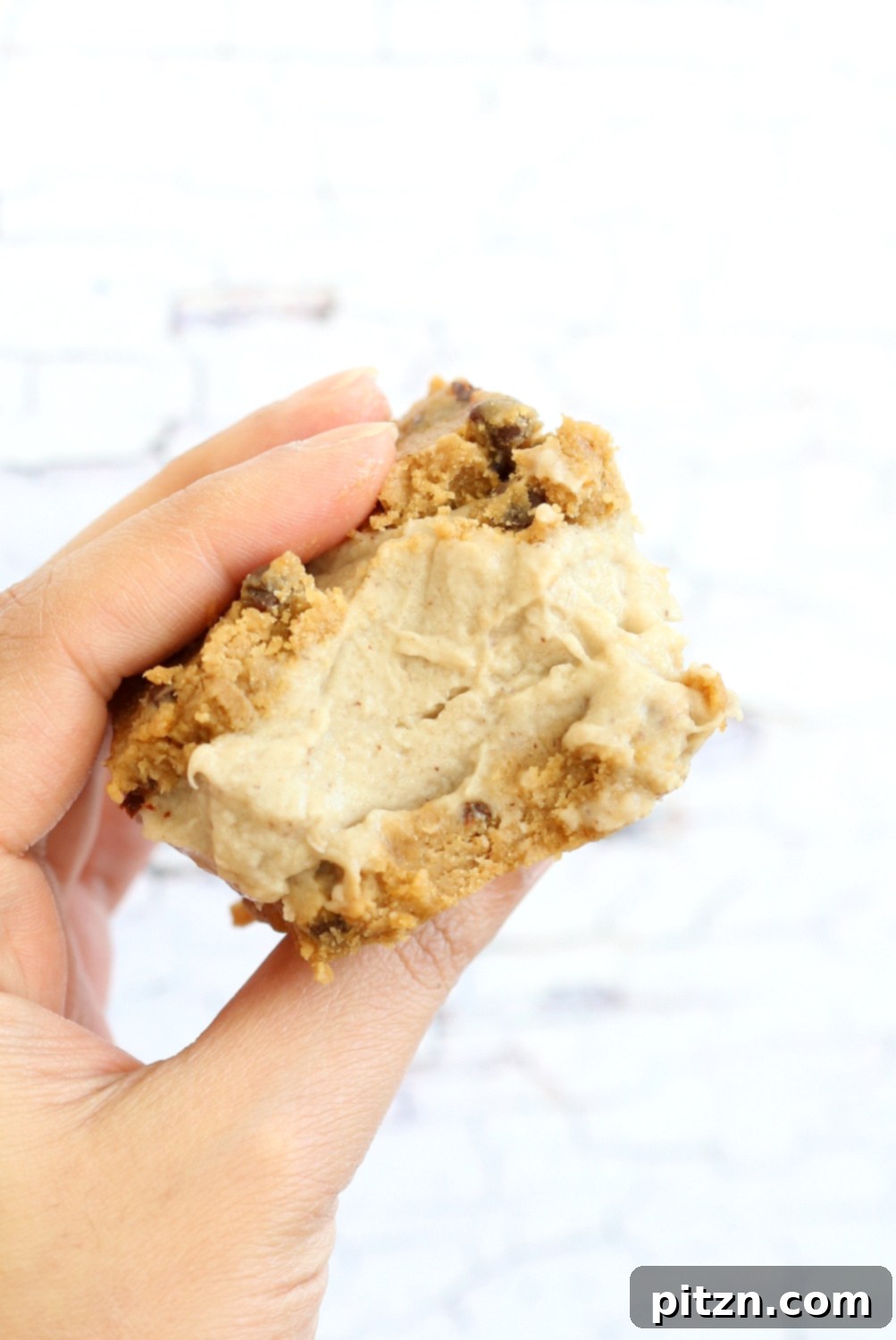 One of our finished Vegan Cookie Dough Ice Cream Sandwiches held in a hand, ready for a delicious bite