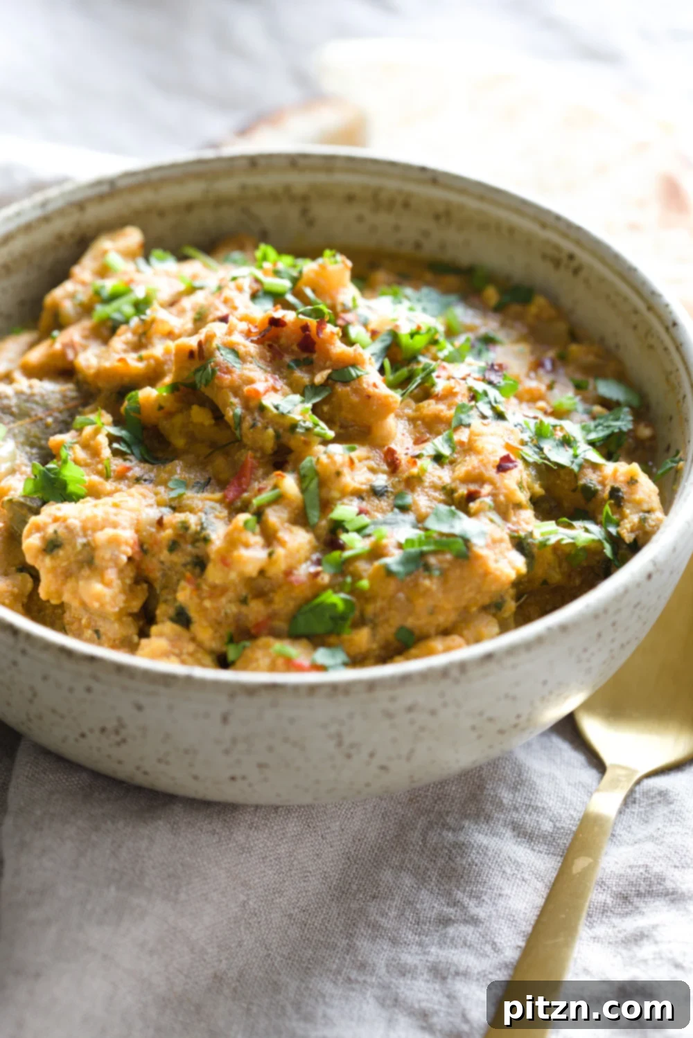 side view of a bowl of creamy vegan methi chicken curry topped with chopped cilantro