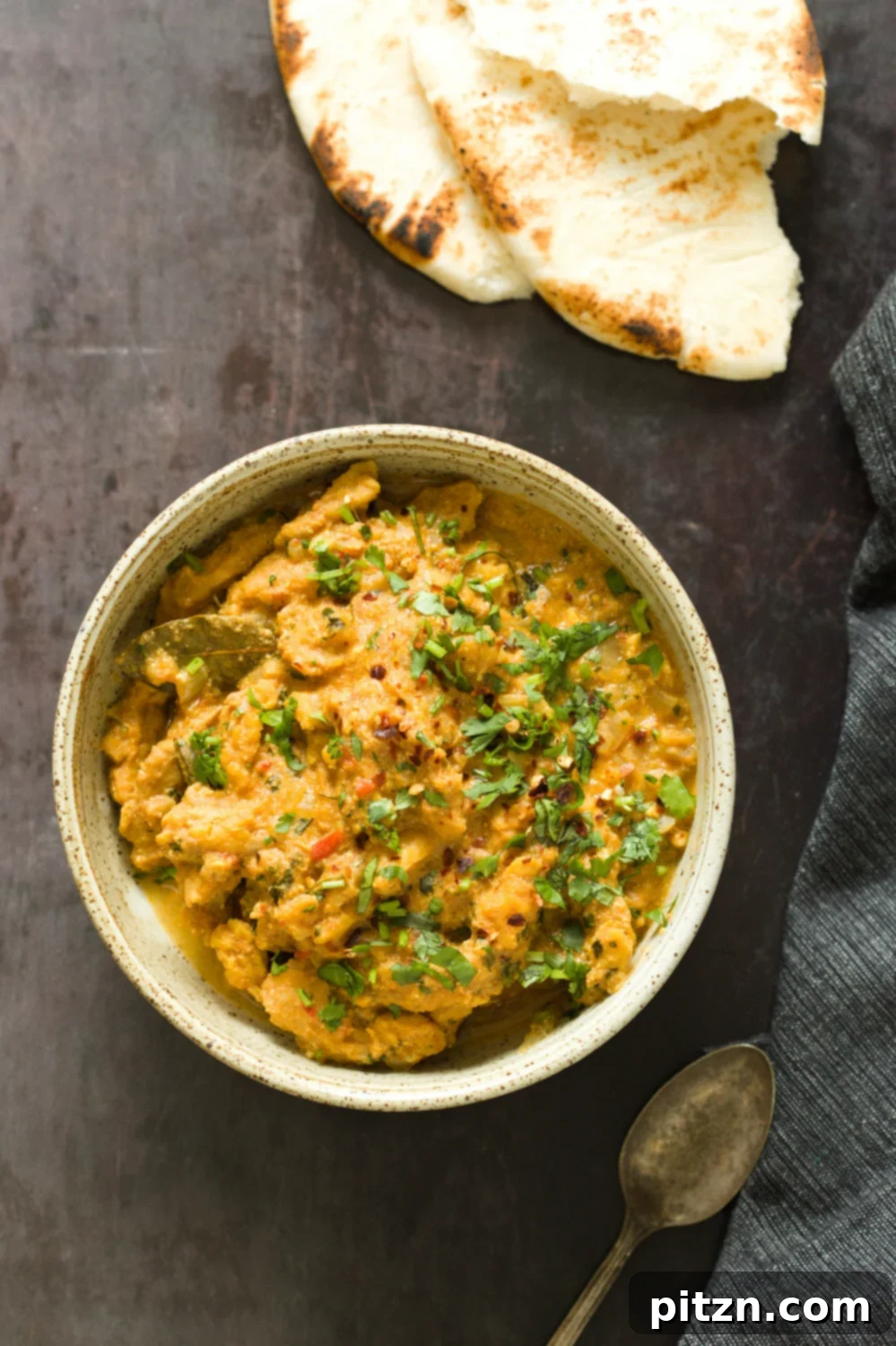 overhead shot of a bowl of vegan methi chicken with some naan bread on the side 