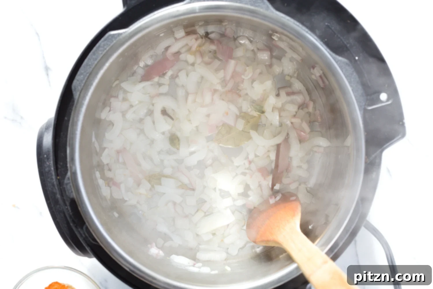 minced onions being sauteed in an instant pot to make vegan curry recipe