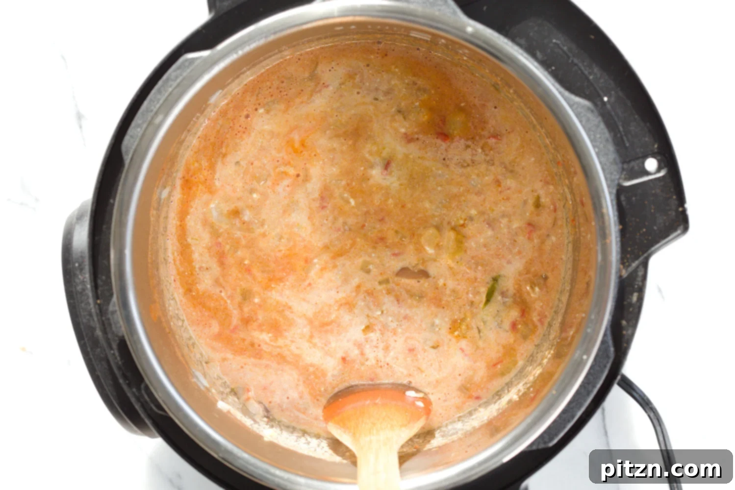 dairy-free milk being stirred into a vegan fenugreek chicken curry made with soy curls