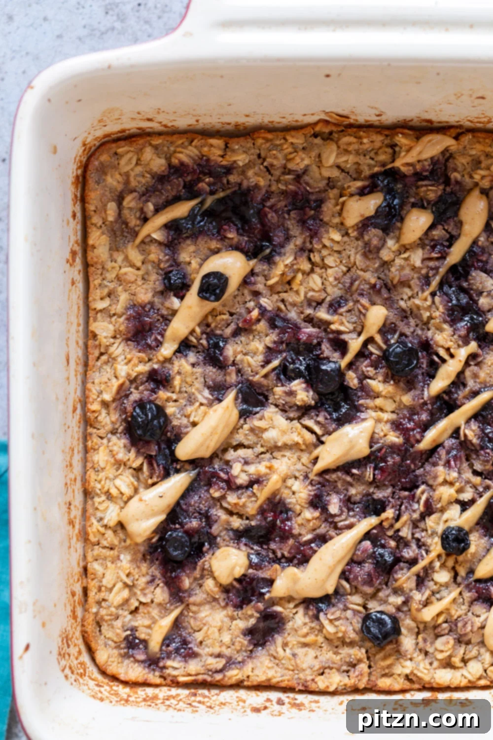 A baking dish filled with unbaked Vegan Peanut Butter and Jelly Oatmeal, showing vibrant swirls of berry jam.