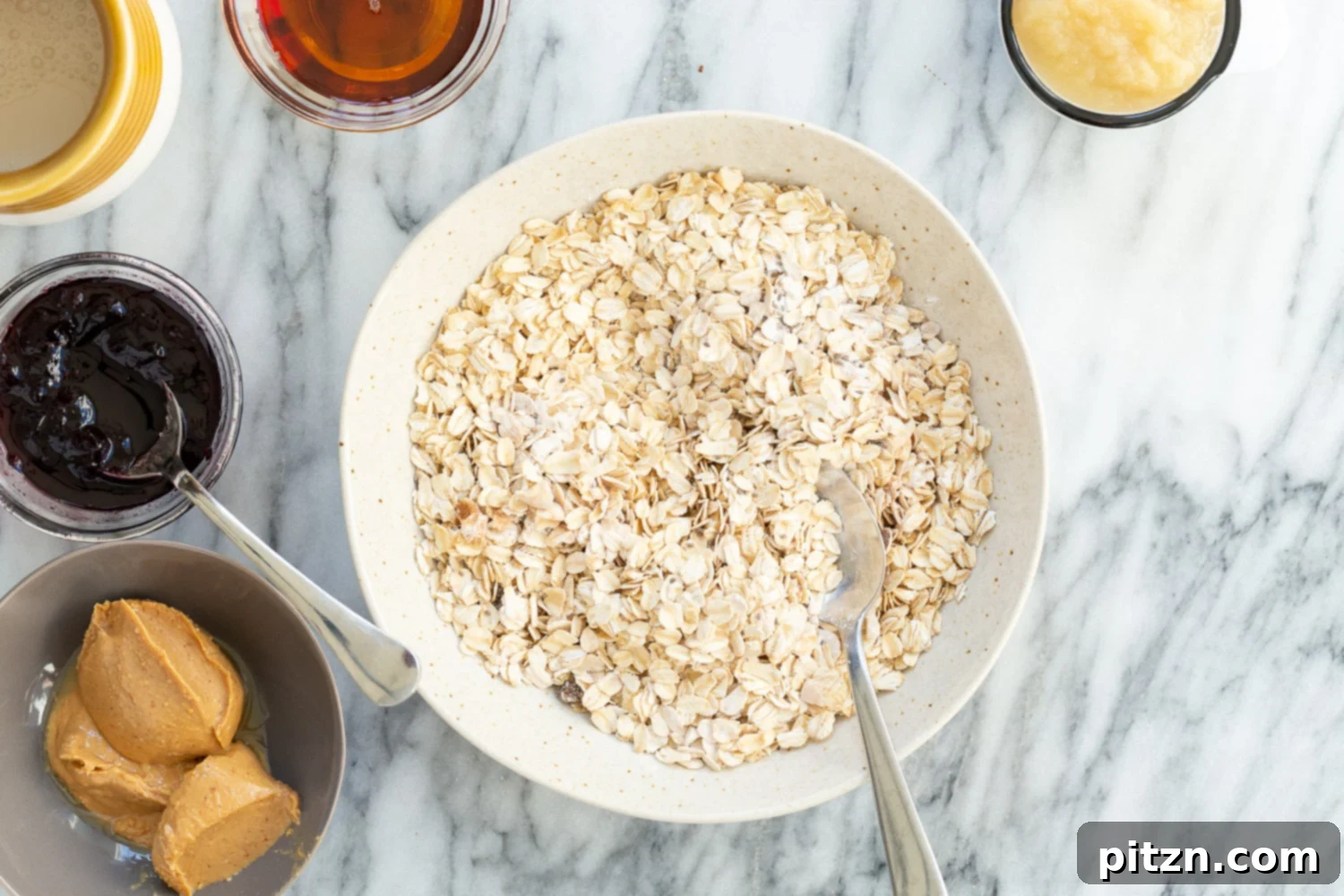 Wet ingredients for Peanut Butter and Jelly Oatmeal in separate bowls, including non-dairy milk, peanut butter, vanilla, maple syrup, and applesauce.