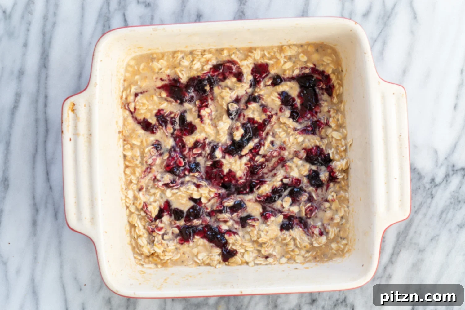 Freshly baked Vegan Peanut Butter and Jelly Oatmeal in a white baking dish, golden brown and ready to be served.