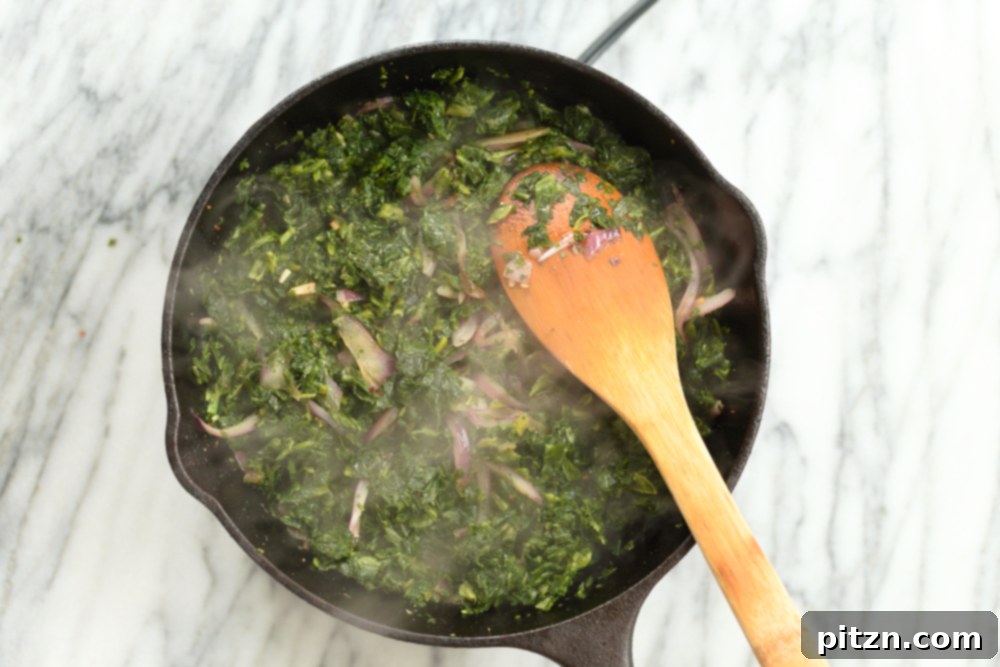 Spinach getting cooked in cast iron skillet