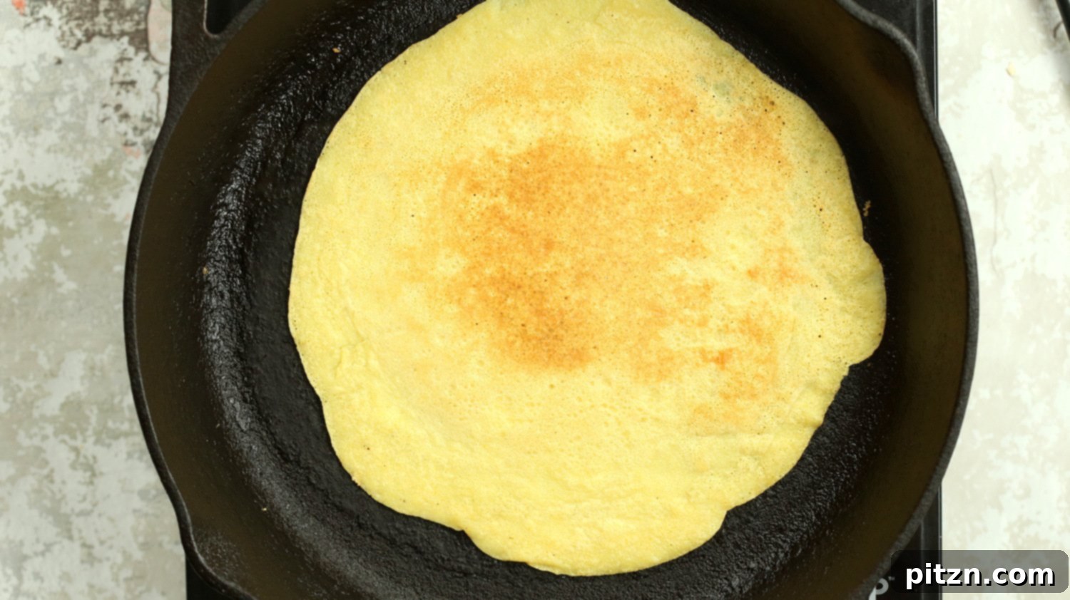 A simple, unadorned Vegan Omelet made from Mung Beans cooking to perfection in a cast iron skillet